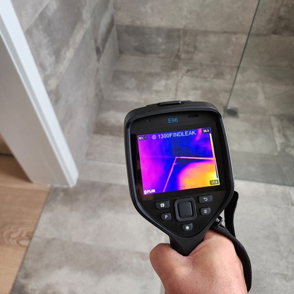 A professional plumber in Nowra using thermal imaging technology to pinpoint water leaks behind walls.